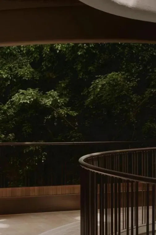 A quiet wooden corridor opening onto a dark green garden.