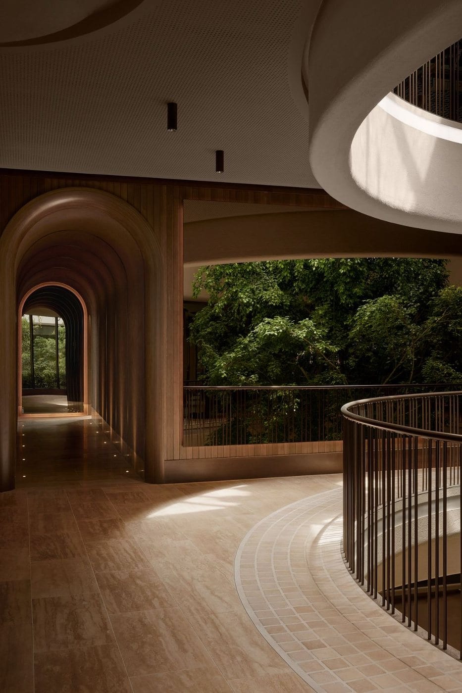 A warm hallway of wooden arches opening onto a green garden.