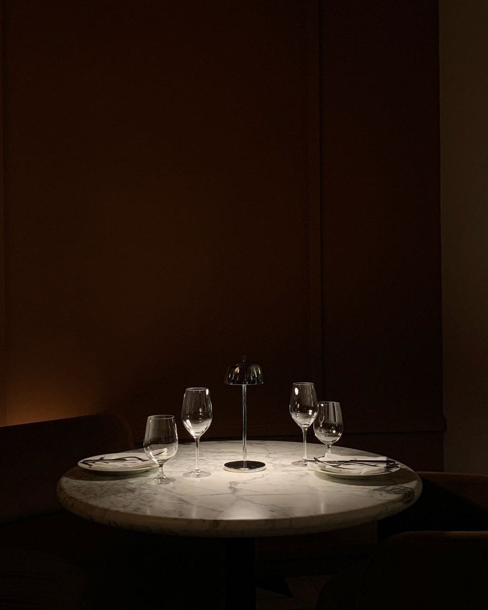 A candlelit table set for two in a dark room.